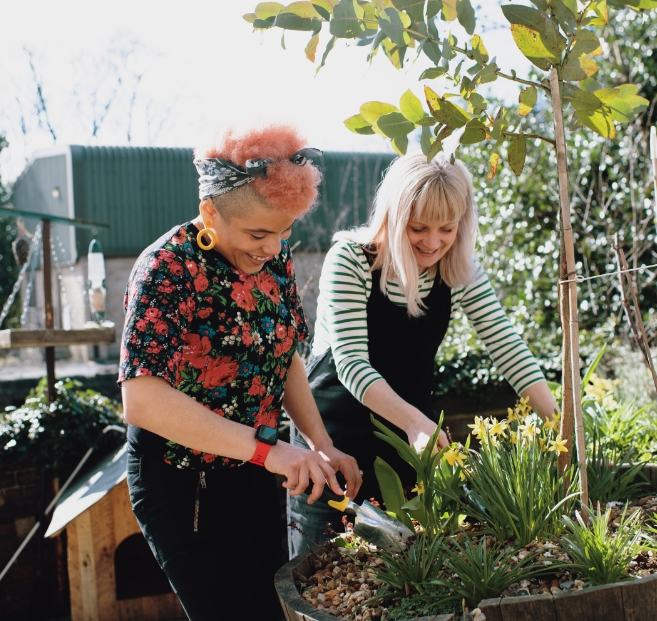 Two women smiling together while gardening.