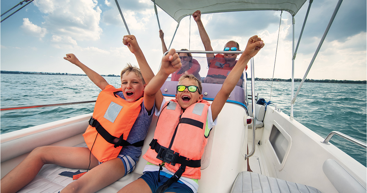 kids in lifejackets having fun on a boat