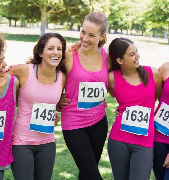 Group of women after a race wrapping arms around each others shoulders