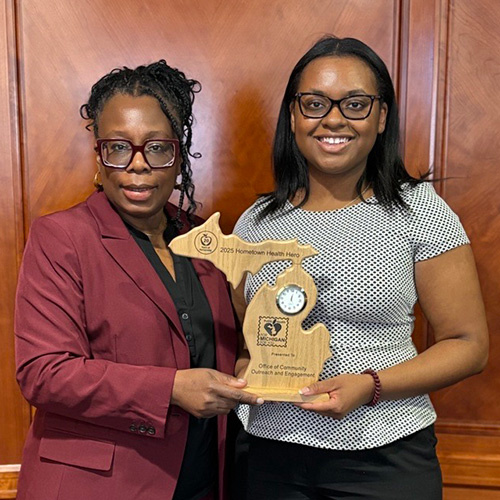 Hayley Thompson, Ph.D., and Brittany Dowe accepted the Hometown Health Hero Award on behalf of the Office of Community Outreach and Engagement at Karmanos Cancer Institute.