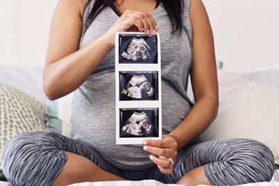 pregnant woman holding ultrasound images