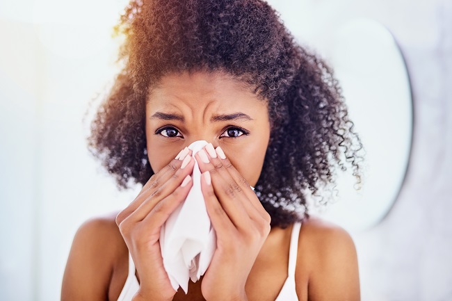 woman sneezing into tissue