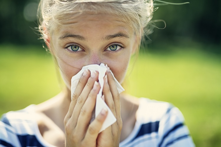 woman sneezing into tissue