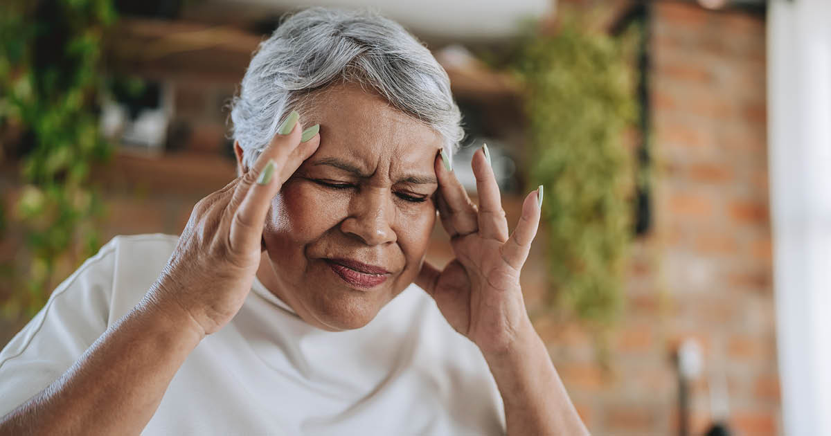 Woman making a face of pain and rubbing her head